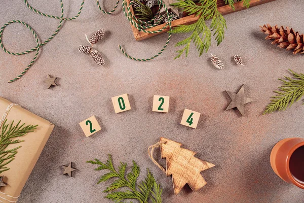 Winter holiday mood, Merry Christmas, Happy New Year background. Preparation for holidays. Handmade gift box, wooden box with Christmas decor and numbers 2024. Flat lay, top view