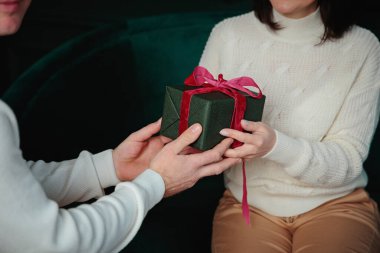 Sevilen bir kadına yeşil bir hediye kutusu veren bir adam.