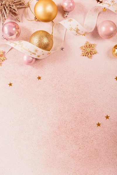 Altın, pembe takılar, kurdeleler ve yıldızlarla dolu Noel ve yeni yıl arkaplanı. Mutlu Noeller yazılı beyaz kurdele. Düz konum, kopyalama alanı olan üst görünüm