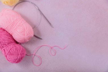 Yumuşak sarı, pembe yün iplik ve örgü iğneleriyle örgü örme hobisi. Pastel renklerde yün yumaklarla dolu bir hayat. Üst görünüm, kopyalama alanı olan düz uzanma