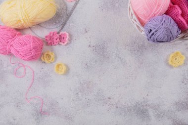 Yumuşak sarı, pembe yün iplik ve örgü iğneleriyle örgü örme hobisi. Pastel renklerde yün yumaklarla dolu bir hayat. Üst görünüm, kopyalama alanı olan düz uzanma