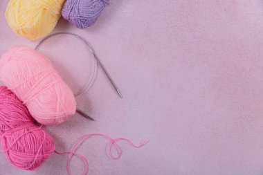 Yumuşak sarı, pembe yün iplik ve örgü iğneleriyle örgü örme hobisi. Pastel renklerde yün yumaklarla dolu bir hayat. Üst görünüm, kopyalama alanı olan düz uzanma