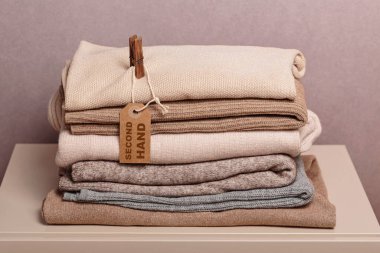 Giysi yığını, kullanılmış kostüm ve ikinci el yazıyla etiketlenmiş. Dairesel moda, hızlı moda, kıyafet geri dönüşümü, çevre dostu sürdürülebilir alışveriş, yeniden satış, ikinci el mağazaları konsepti