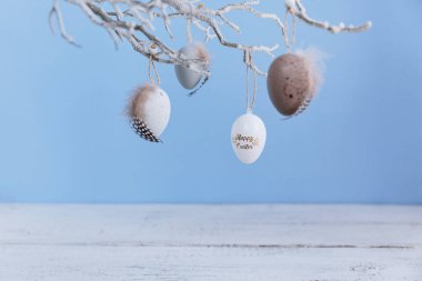 Pastel mavi arka planda asılı Paskalya yumurtaları. Paskalya dekorlu reklam ürünleri için hazırlan. Kopya alanı olan Mutlu Paskalyalar veya davetiye kartları