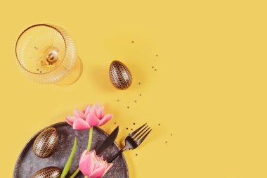 Masa takımı, boş bardaklar, pembe laleler ve sarı arka planda bayramlık paskalya dekoru. Mutlu Paskalyalar ya da davetiyeler. Üst görünüm, düz görünüm, metin için alanı kopyala