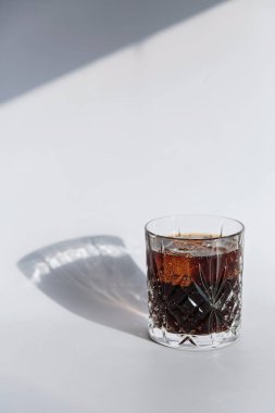 Viski kola kokteyli, sert alkol ve buzlu viski bardağı, beyaz arka planda sert ışık.