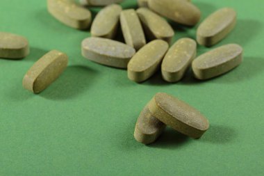 Herbal and Vitamin green pills healthy food freely laid on green background for healthy eating in daily life