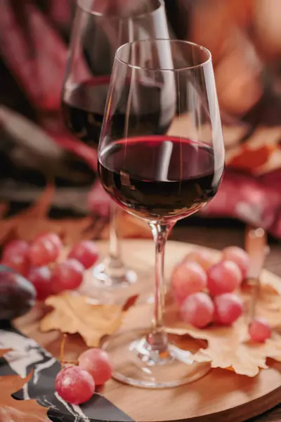 秋はまだ暗い木の背景に素朴なスタイルで赤ワイン ブドウ 乾燥葉の2つのメガネで生きています コピースペースを備えたロマンチックなセーター気象コンセプト — ストック写真