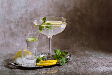 Gümüş tepside buzlu, limonlu ve nane arkaplanlı temiz soğuk içeceklerle dolu çeşitli bardakların toplanması. Kokteyl partisi, alanı kopyala