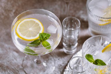 Gümüş tepside buzlu, limonlu ve nane arkaplanlı temiz soğuk içeceklerle dolu çeşitli bardakların toplanması. Kokteyl partisi, yaklaşın.