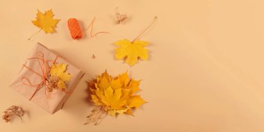 Sonbahar yaratıcı tatil hediyesi. El yapımı kağıt hediye kutusu ve bej masa üzerinde yapraklar. Hediye paketi. Şükran Günü, sonbahar tatili, sonbahar geçmişi