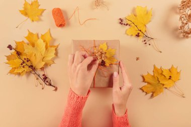 Kurumuş yapraklarla hediyeleri paketleme ve dekore etme süreci. El işi kağıdında hediye kutuları ve doğal sonbahar süslemeleri, yaratıcı ve sıfır atık tatil hediye paketi. DIY kavramı