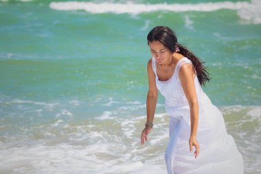 Tasasız bir terk ile, orta yaşlı bir kadın dalgalarla dans ediyor, deniz kenarındaki mutluluğun tadını çıkarıyor..