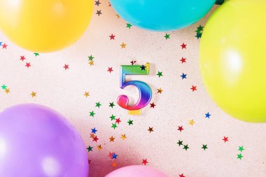 5 numaralı gökkuşağı, renkli balonlar ve yıldız şeklinde konfetilerle çevrili, doğum günü veya yıldönümü kutlamaları için mükemmel bir arka plan..