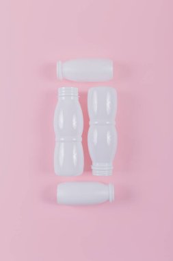 Pembe arka plana serilmiş beyaz plastik şişeler, çevreyi koruma ve plastik atıkları en aza indirme çabalarını gösteriyor.