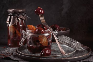 Marinated plums with spices in glass jar on the kitchen table. Homemade canning. Vegetable snack for winter.