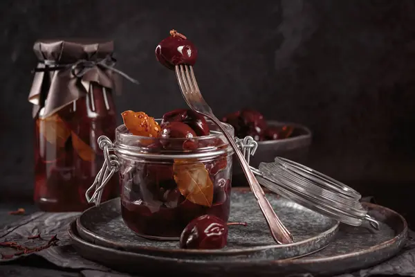 Marinated plums with spices in glass jar on the kitchen table. Homemade canning. Vegetable snack for winter.