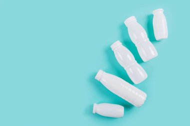 Mavi arka planda beyaz plastik şişelerin üst görüntüsü, sıfır atık yaşam ve çevre dostu alışkanlıkları temsil ediyor.