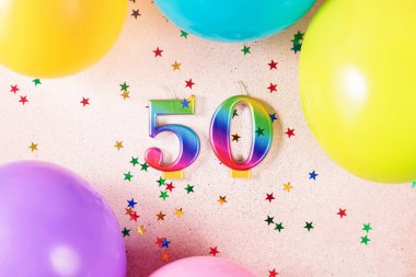 50 numaralı parlak gökkuşağı, çok renkli balonlar ve etrafa saçılmış yıldız konfetileri ile parlak ve neşeli bir parti düzenlemek özel durumlar için ideal..