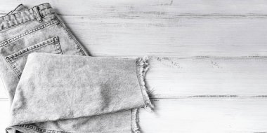 Beyaz arka planda gri kot pantolon yığını. İkinci el giyim mağazası. Dairesel moda, çevre dostu sürdürülebilir alışveriş, ikinci el mağazaları konsepti. Metin için boş kopyalama alanı