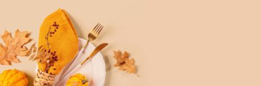 Arka planda balkabağı süslemeleri olan sonbahar masası ayarı. Boş tabak, sarı peçete ve kuru yapraklar. Sonbahar tatili havası, Cadılar Bayramı, Şükran Günü afişi fotokopi alanı