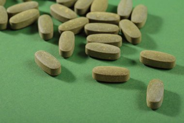 Herbal and Vitamin green pills healthy food freely laid on green background for healthy eating in daily life