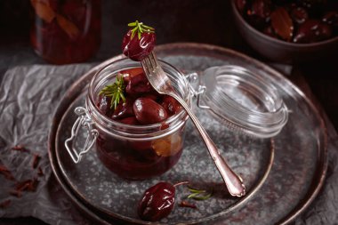 Marinated plums with spices in glass jar on the kitchen table. Homemade canning. Vegetable snack for winter.
