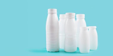 Beyaz plastik şişeler mavi arka planda sergileniyor, çevresel sorumluluk duygusu uyandırıyor ve sürdürülebilir ambalaj çözümlerine ihtiyaç duyuluyor.