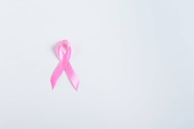 Beyaz bir yüzeye yerleştirilmiş pembe kurdelenin detaylı bir görüntüsü göğüs kanseri farkındalığını simgeliyor. Eğitim materyalleri, tıbbi sunumlar ve hayır işleri için mükemmel..