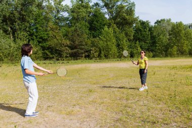 Genç çocuk güneşli bir günde badminton maçı için hazırlanıyor.