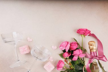 İçinde iki şampanya kadehi, pembe güller, bir şampanya şişesi ve romantik hediye kutularının olduğu güzel bir daire..