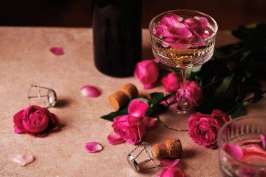 Romantik bir kompozisyon. İçinde gül yaprakları, bir şişe köpüklü şarap ve dağınık güller var. Sevgililer Günü için ideal..