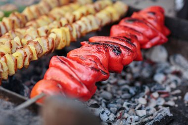 Kömürün üzerinde ızgara yapan çeşitli et, sebze ve sosislerle karışık şişler. Mangal ziyafeti için mükemmel bir lezzet ve görsel çeşitlilik sağlıyor..