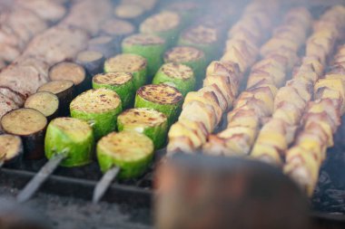 Kabak, patlıcan ve kömürün üzerinde ızgara yapan patates dilimli sebze şişleri. Lezzetli bir barbekü deneyimi için dokuları ve kömürleri vurgulanıyor..