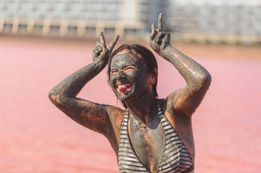 Pembe gölde neşeli spa anlarında dilinde çifte barış işareti olan bir kadın.