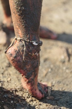 Ayak ve ayak bilekleri mineral çamura bulanmıştı. Doğal kaplıca tedavisi sırasında kumlu zeminde bileklik vardı.