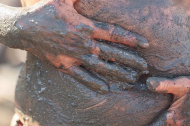 Doğal iyileşme ve detoks derisi için mide üzerine ıslak mineral çamuru dökerek yakın plan.