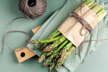 Mutfak sicimi olan yeşil havlunun üzerinde düz bir kuşkonmaz yığını.