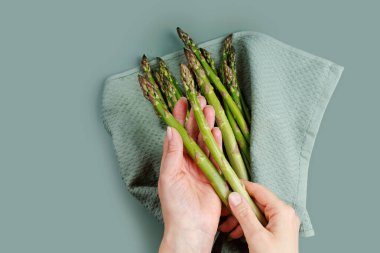 Pişirme ya da salata hazırlıkları sırasında elleri mavi havlunun üzerinde nazikçe taze kuşkonmaz tutuyor.