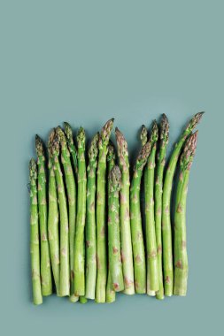 Mavi bir yüzey üzerinde dikey yeşil kuşkonmaz sapları ve sağlıklı yemek temaları için uygun kopya alanı