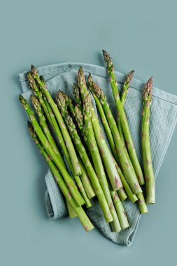 Yıkandıktan ve hazırlandıktan sonra yumuşak bir mutfak havlusuna serilmiş yeşil kuşkonmaz mızrakları.