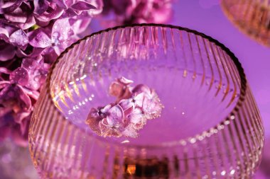 Havada süzülen leylak çiçekleri dokulu kristal bir bardakta ışıl ışıl şarapla doludur.