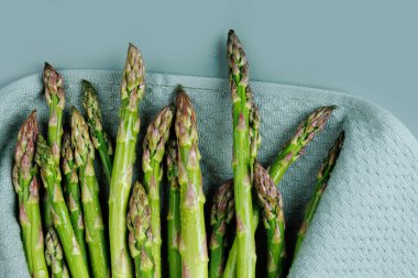 Mutfak havlusuna sarılı taze ıslak kuşkonmaz manzarası mutfak hazırlama sürecini gösteriyor.