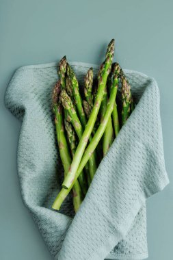 Pişirme hazırlığı ya da sağlıklı yaşam tarzı konsepti için yumuşak mutfak havlusuna yerleştirilmiş çiğ kuşkonmaz demetinin üst görüntüsü