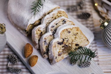 Yakın plan, toz şekerle süslenmiş, çam iğneleri, bademler, kozalaklar ile süslenmiş ahşap bir tahtaya kurulmuş, ve rahat arka planda bulanık, neşeli ışıklar..
