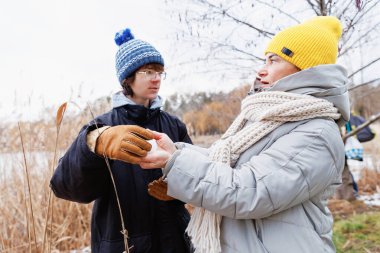 Genç bir çocuk ve anne dışarıda huzurlu bir şekilde birbirlerine bakarken bir kartopu değiş tokuşu yapıyorlar.