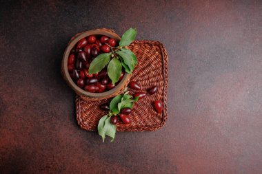 Kornelian kiraz meyvelerinin ahşap kasede dokuma tepsisinde yaprakları var.