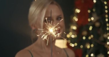 Çekici, sarışın, evde fotoşop yapan, dekore edilmiş yılbaşı ağacının yanında. Parıltı tutan, gülümseyen güzel bir kadın. Yeni yıl ve Noel kavramı.