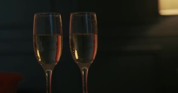 シャンパン2杯のグラスを閉じ スタイリッシュなスタジオでテーブルの上に輝くワインが立っています 人々は 新年を待って 休日を祝う 新年とクリスマスの概念 — ストック動画
