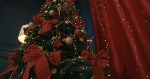 Close Van Prachtige Kerstboom Versierd Met Rode Bogen Bloemenslingers Staan — Stockvideo